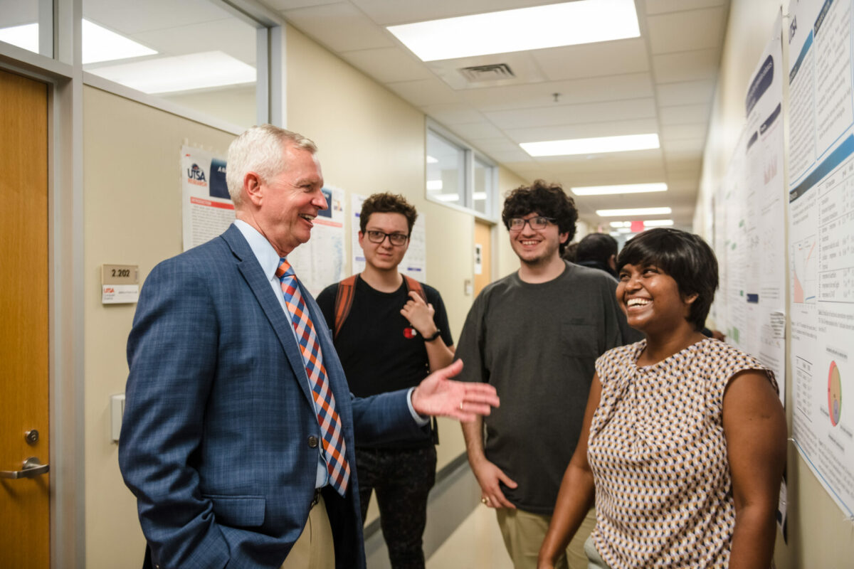 Guy Walsh talks with students during a poster presentation at the North Paseo Building.