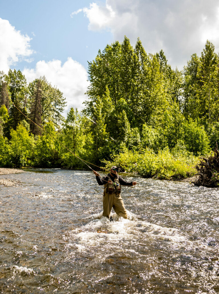 Sean Patrick stands in a stream and casts his fly fishing rod.
