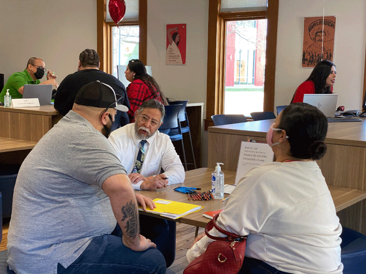 Richard Sifuentes sits at a table with two clients at the UTSA Westside Community Center.