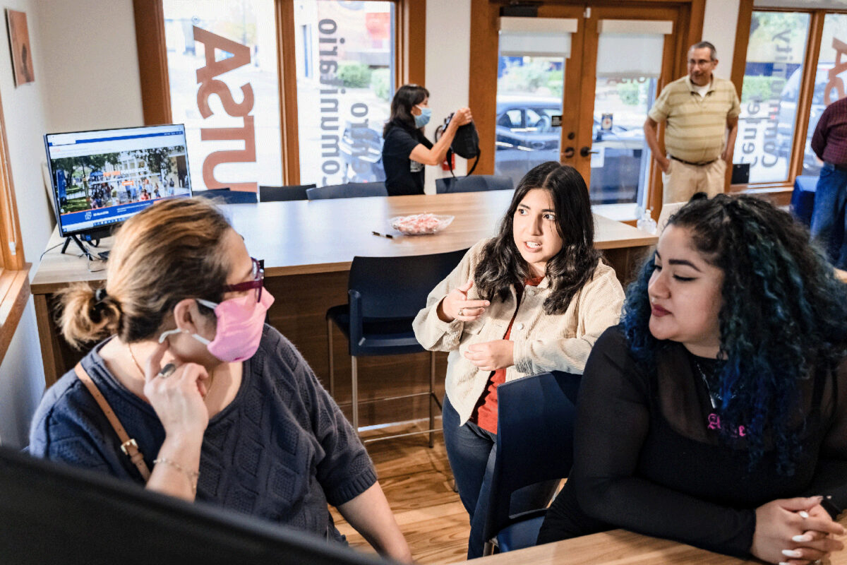 Two students chat with a visitor inside the UTSA Westside Community Center.