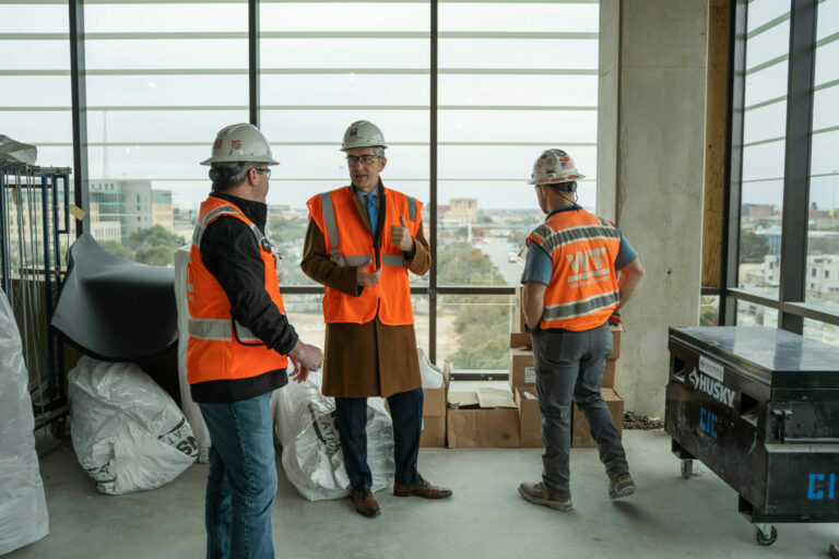 David Mongeau stands beside two construction workers as they talk about San Pedro I.