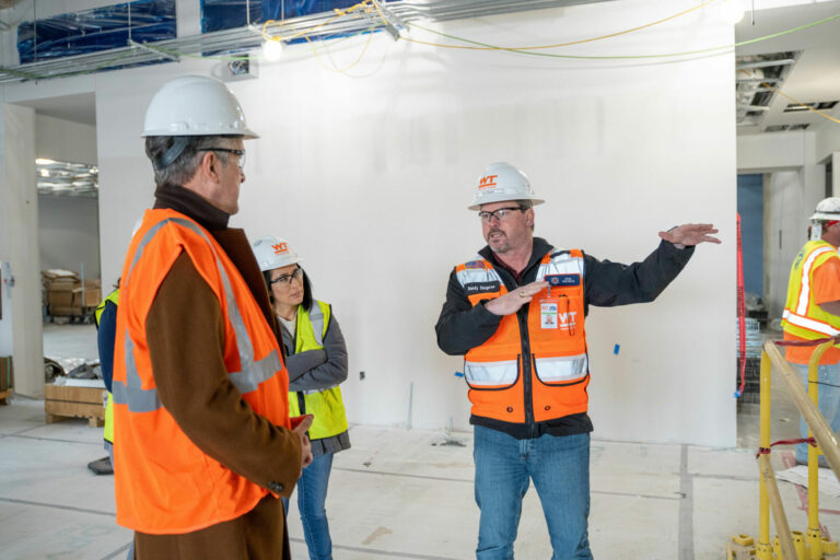 A construction worker points to the right as he speaks to David Mongeau.