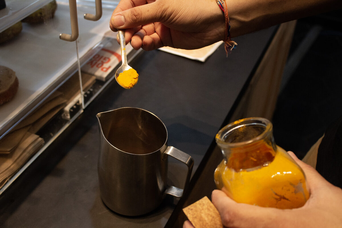 Nirav Amarnath pours a spoonful of turmeric into a tin coffee pot.