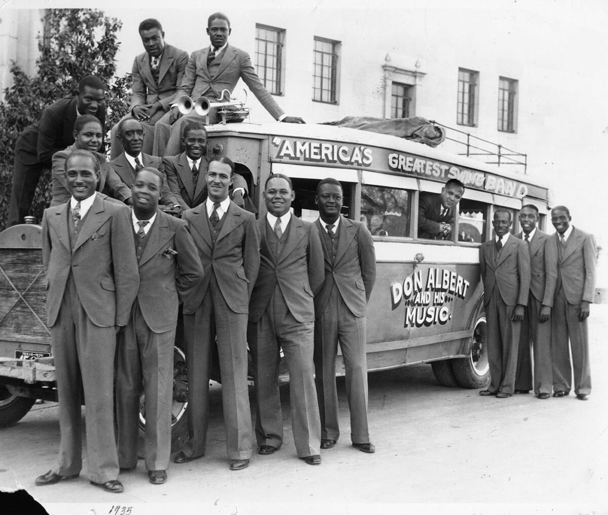 Fifteen musicians surround Don Albert's tour bus to pose for a photo.