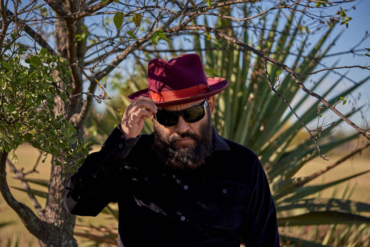 Marco Cervantes adjusts his hat while wearing sunglasses