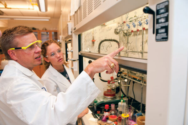 Doug Frantz and a female student analyze a drawing of a chemical structure in a laboratory.