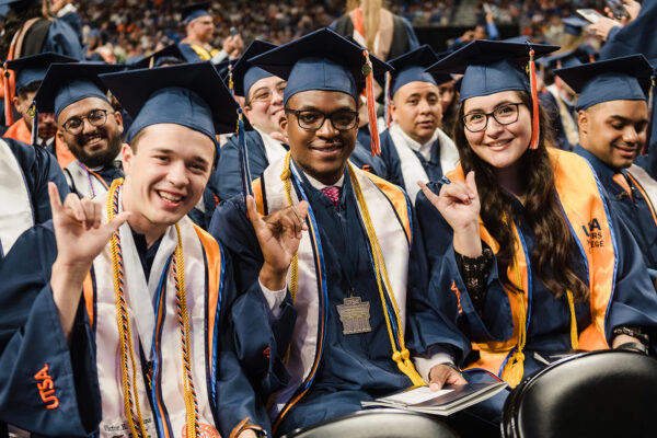 Three UTSA graduates pose for a photo during the Commencement ceremony.