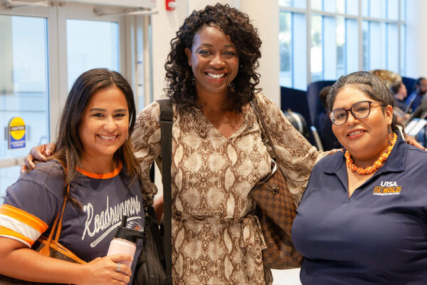 Three UTSA employees smiling as they pose for a photo