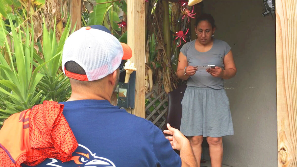 A UTSA volunteer talks to a Westside homeowner about housing resources the university offers.