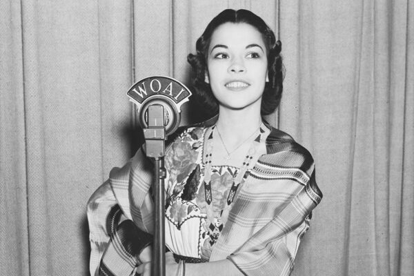 Rosita Fernandez stands in front of a WOAI microphone.
