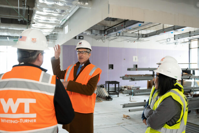 David Mongeau points to the right as he speaks to two construction workers.