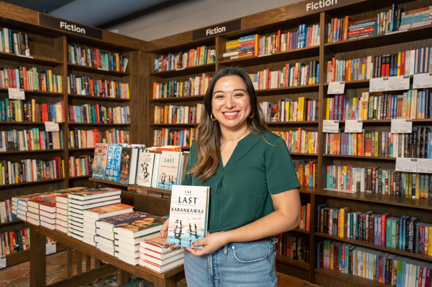 Kimberly Garza smiles while standing in front of bookshelves.