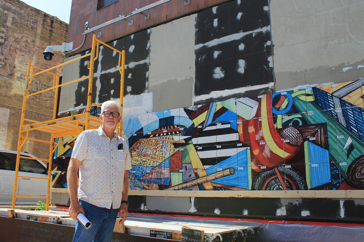 Mark Hogensen stands in front of his half-installed mural