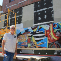 Mark Hogensen stands in front of his half-installed mural