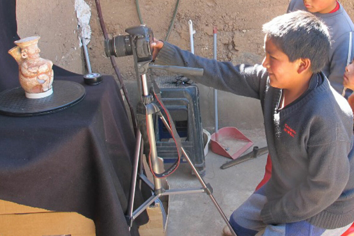 child holding camera pointing at ancient arificact on a rotating base