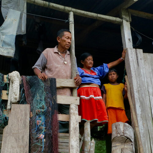 Cofán family standing in doorway of hut