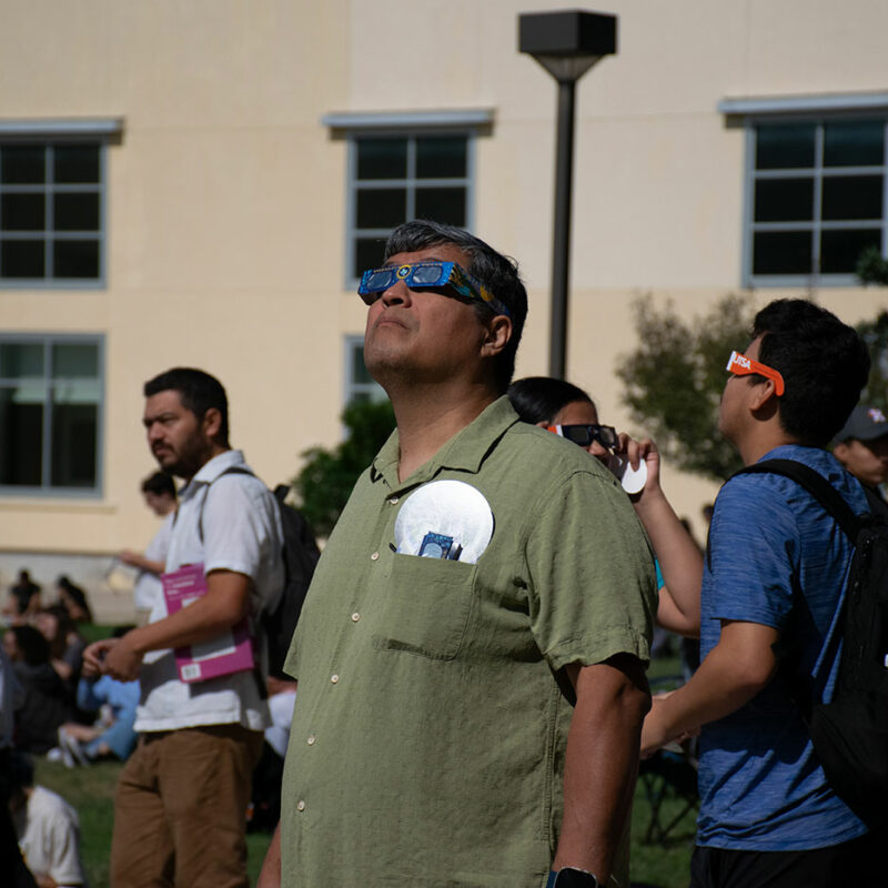 A man looks up at the sky with solar eclipse glasses.