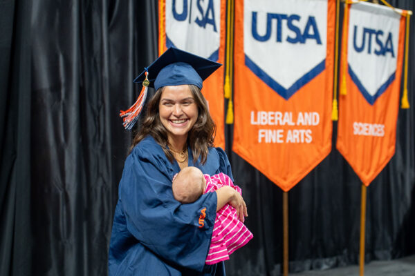 Mariana Rezende Tigre Cheatham smiles as she holds her baby on the Commencement stage