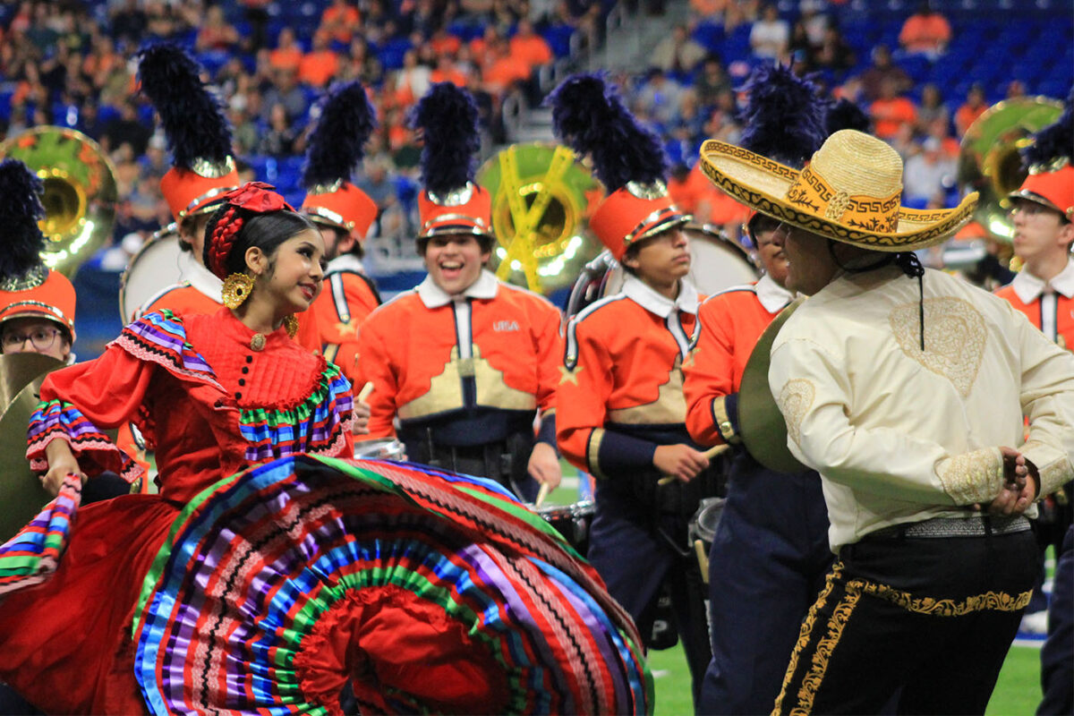 A young woman swings her colorful Jalisco style dress while dancing with a man in a sombrero