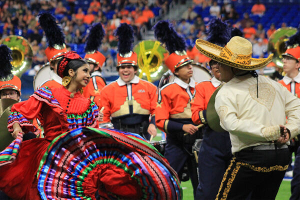 A young woman swings her colorful Jalisco style dress while dancing with a man in a sombrero