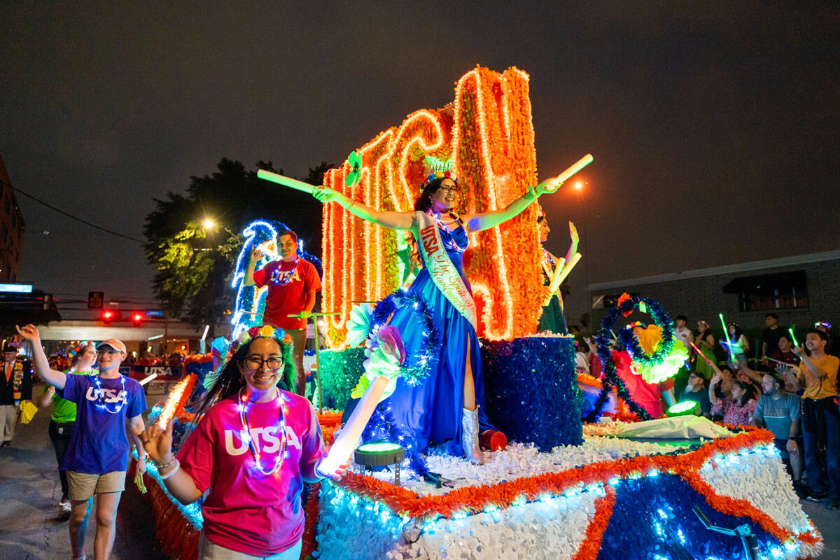 Alondra Castillo holds up glow sticks on UTSA's parade float