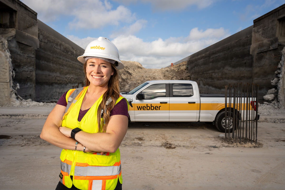 Bonnie Lee poses in front of a Webber pickup truck at a freeway construction site