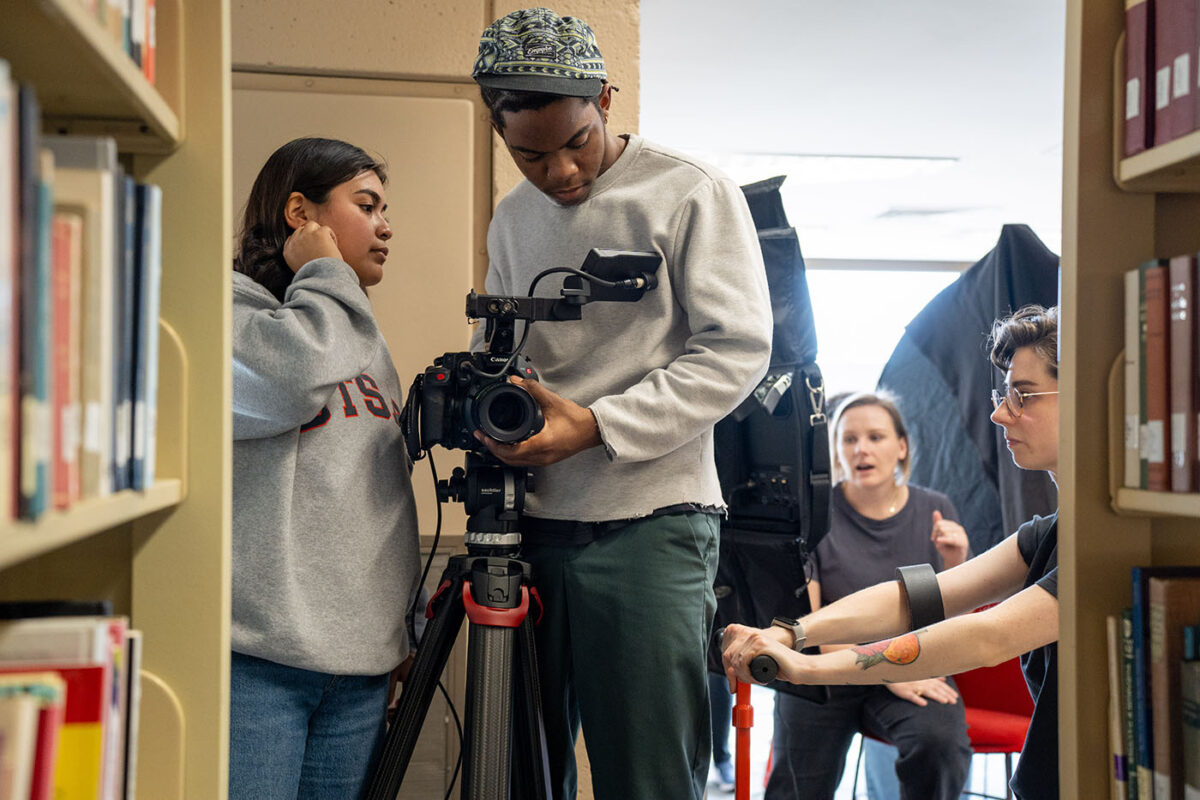 Three students prepare the camera and dolly for an upcoming scene