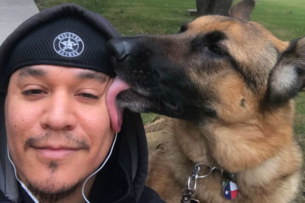 Max, a service dog, licks the cheek of Eloy Rodriguez