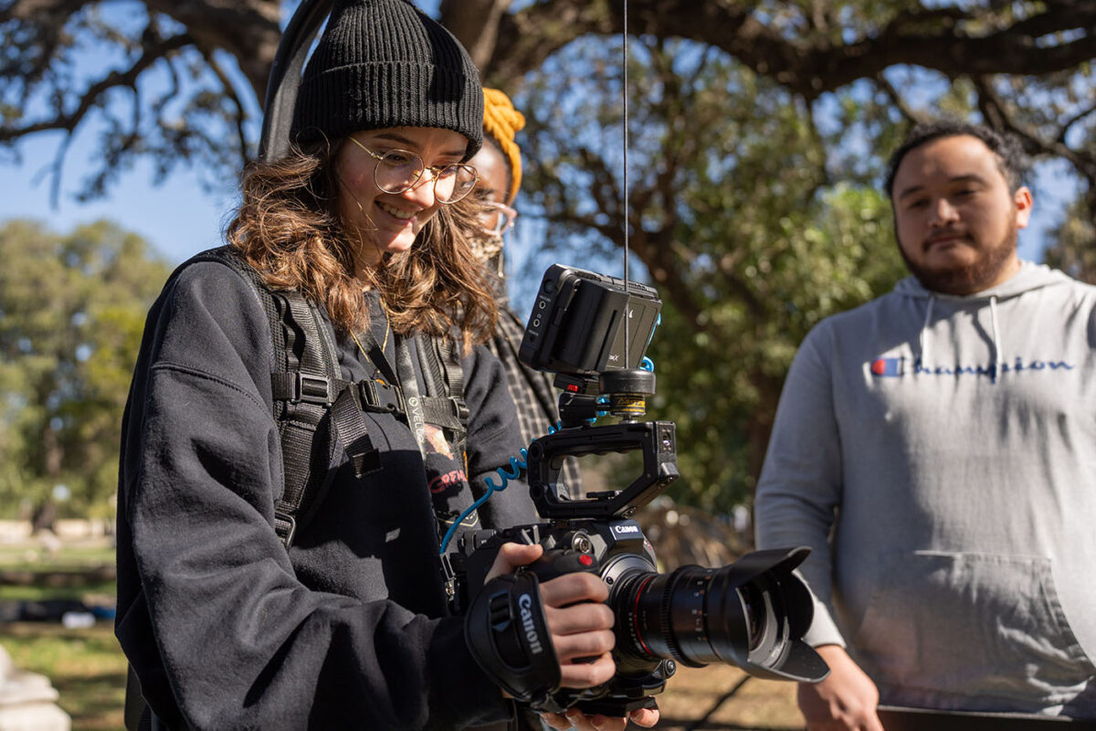 A female film student smiles while operating a camera