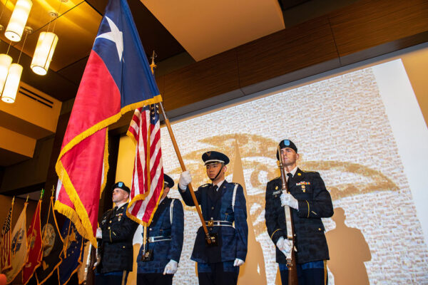 Four service members hold up flags at a UTSA event celebrating veterans