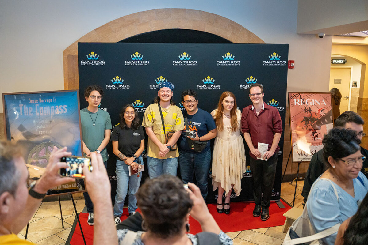 Six students pose for photos on the red carpet