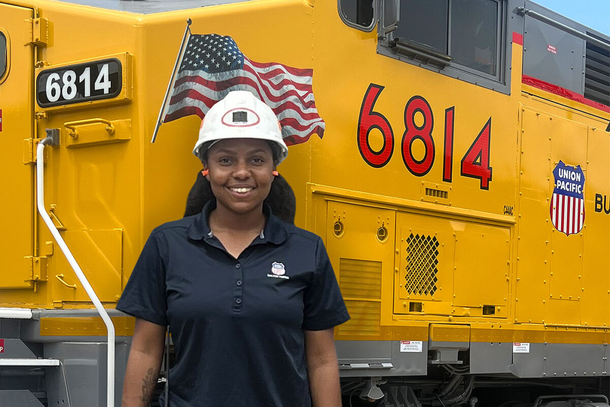 Taylor Richard poses in front of a large yellow locomotive