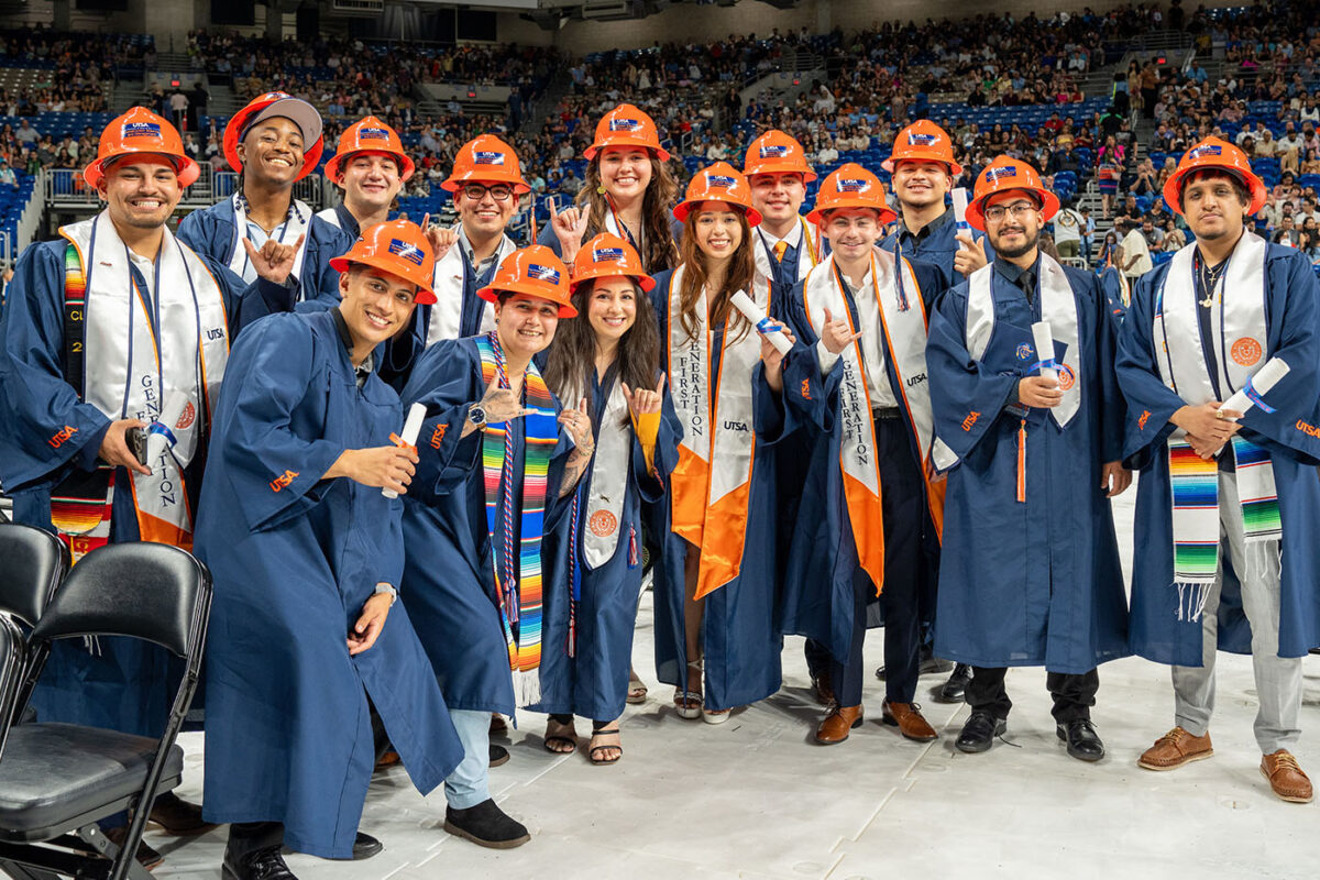 A group of UTSA graduates wearing orange hard hats