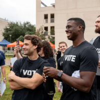 Spurs players and staffers smile while watching their teammates pose for photos.