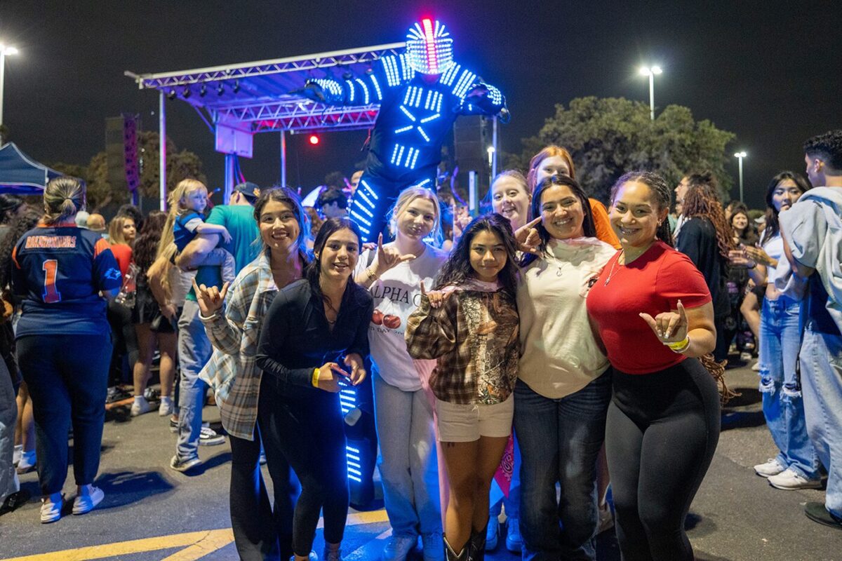 Group of people stand in front of music stage.