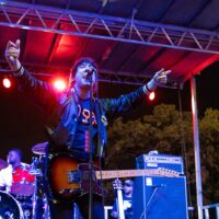 Man raises arms up as he sings into microphone.