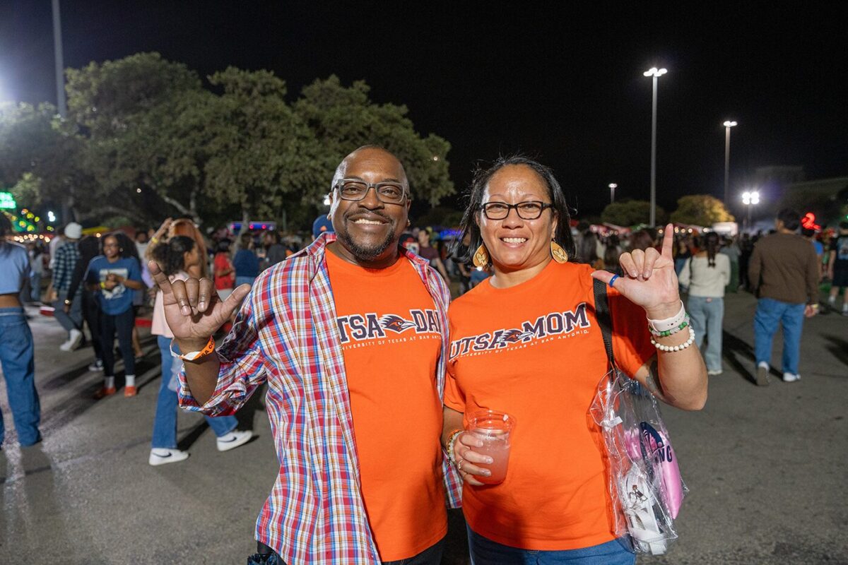 Two people raise their hands up and smile.