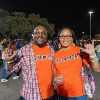 Two people raise their hands up and smile.