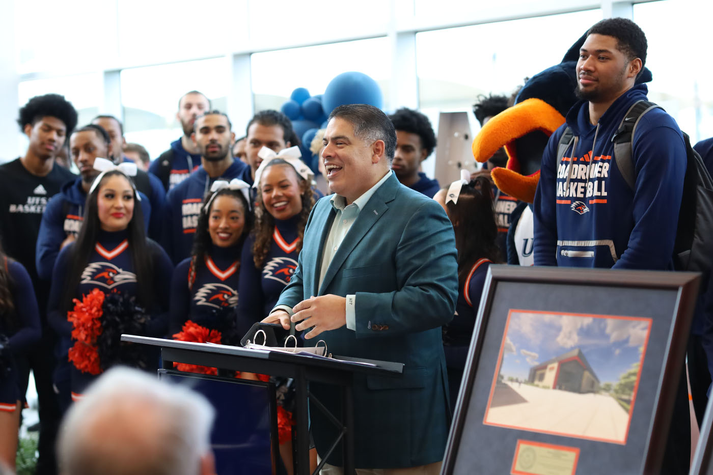 Manny Pelaez speaks in front of a large group of UTSA student-athletes