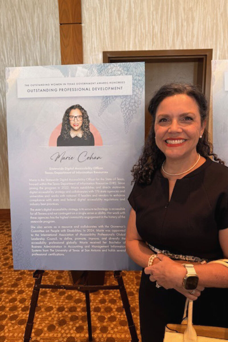 Marie Cohan smiles next to a poster on an easel