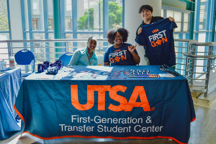 Students offer UTSA First Gen t-shirts at a table