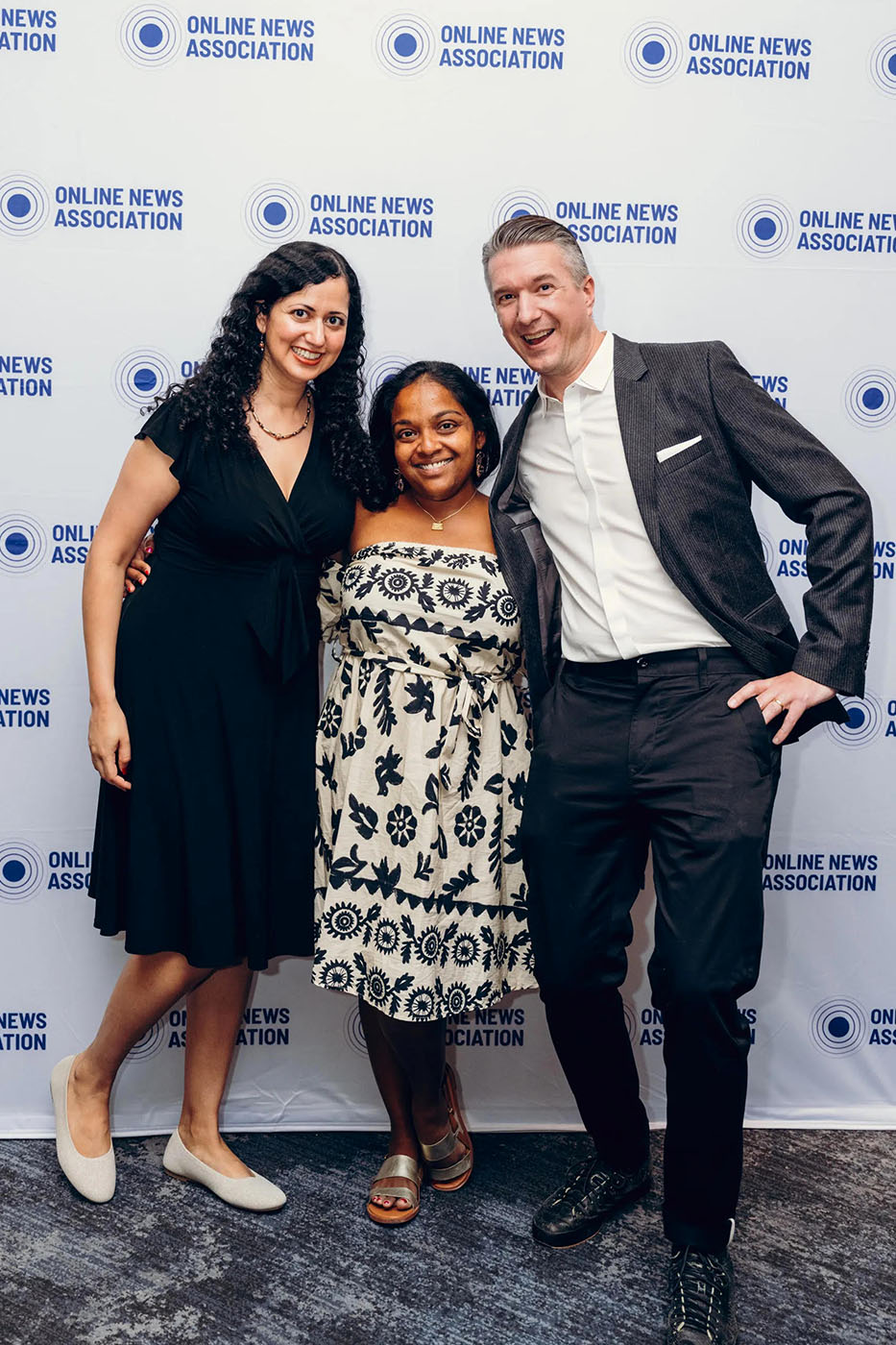 Three people posing in front of an Online News Association backdrop