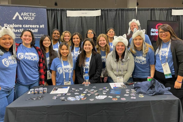 15 Women in Cybersecurity event attendees smile during a group photo