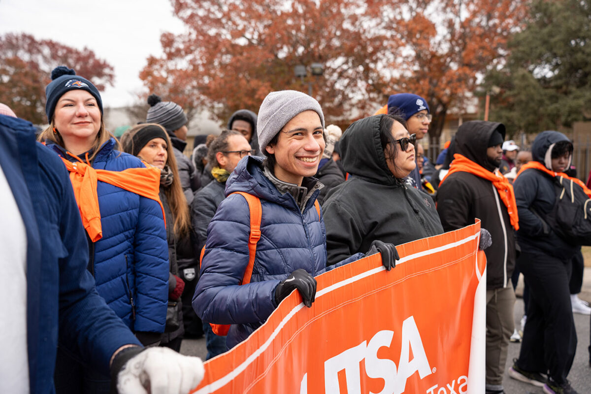 A person holds a banner and smiles