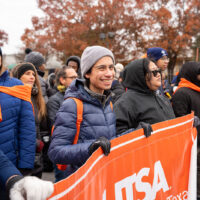 A person holds a banner and smiles