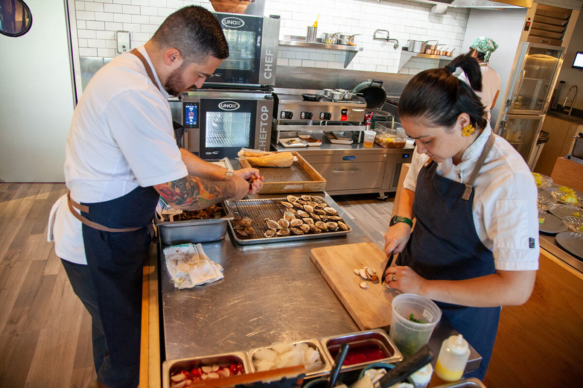 A man and woman stand in a kitchen.