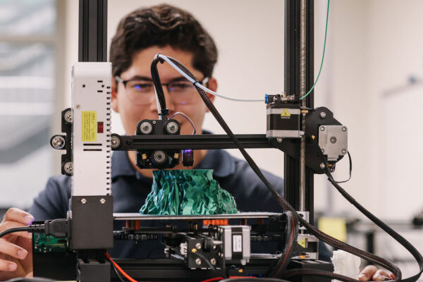 A student watches a 3D printer.