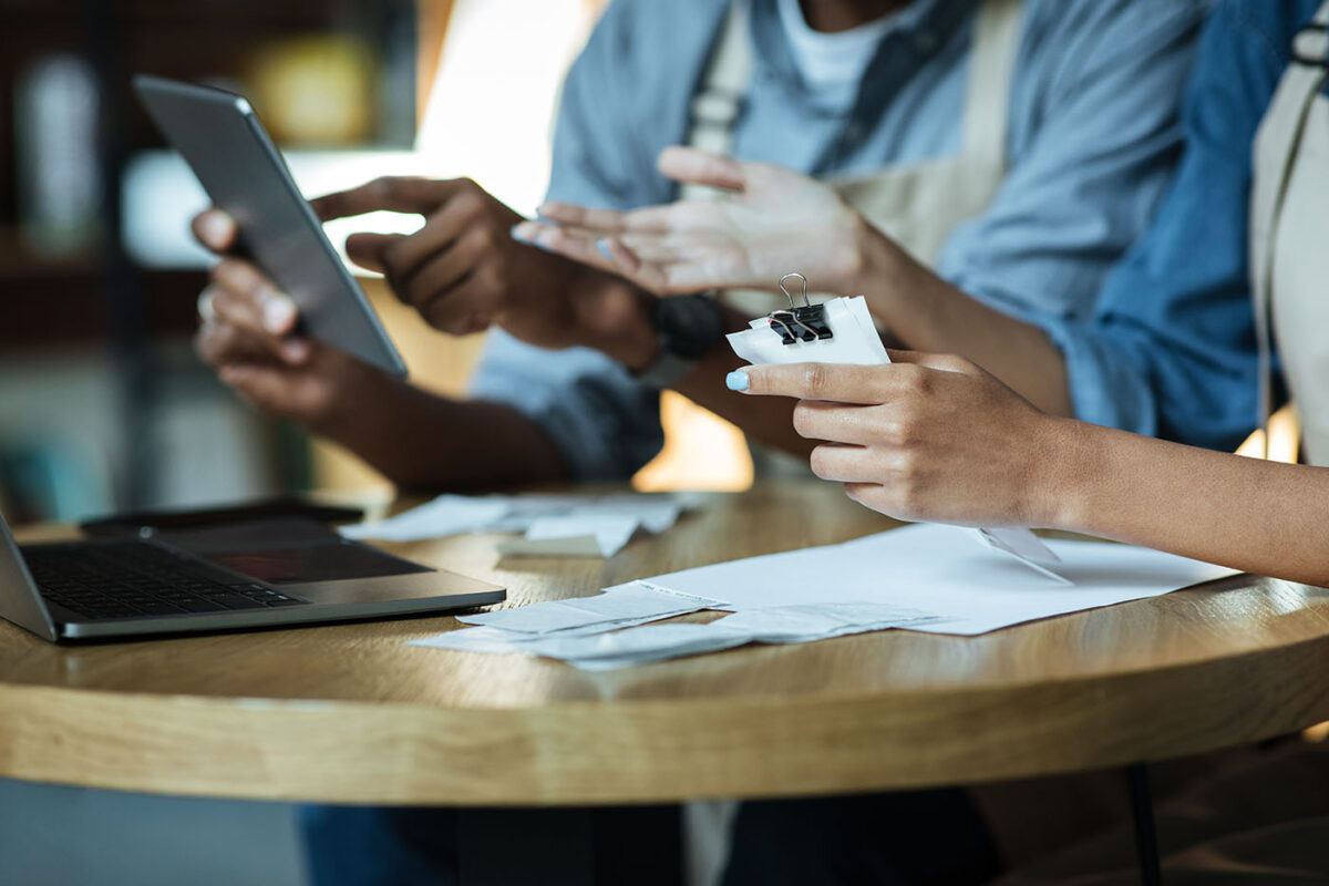 Two small business employees look at a tablet and financial papers