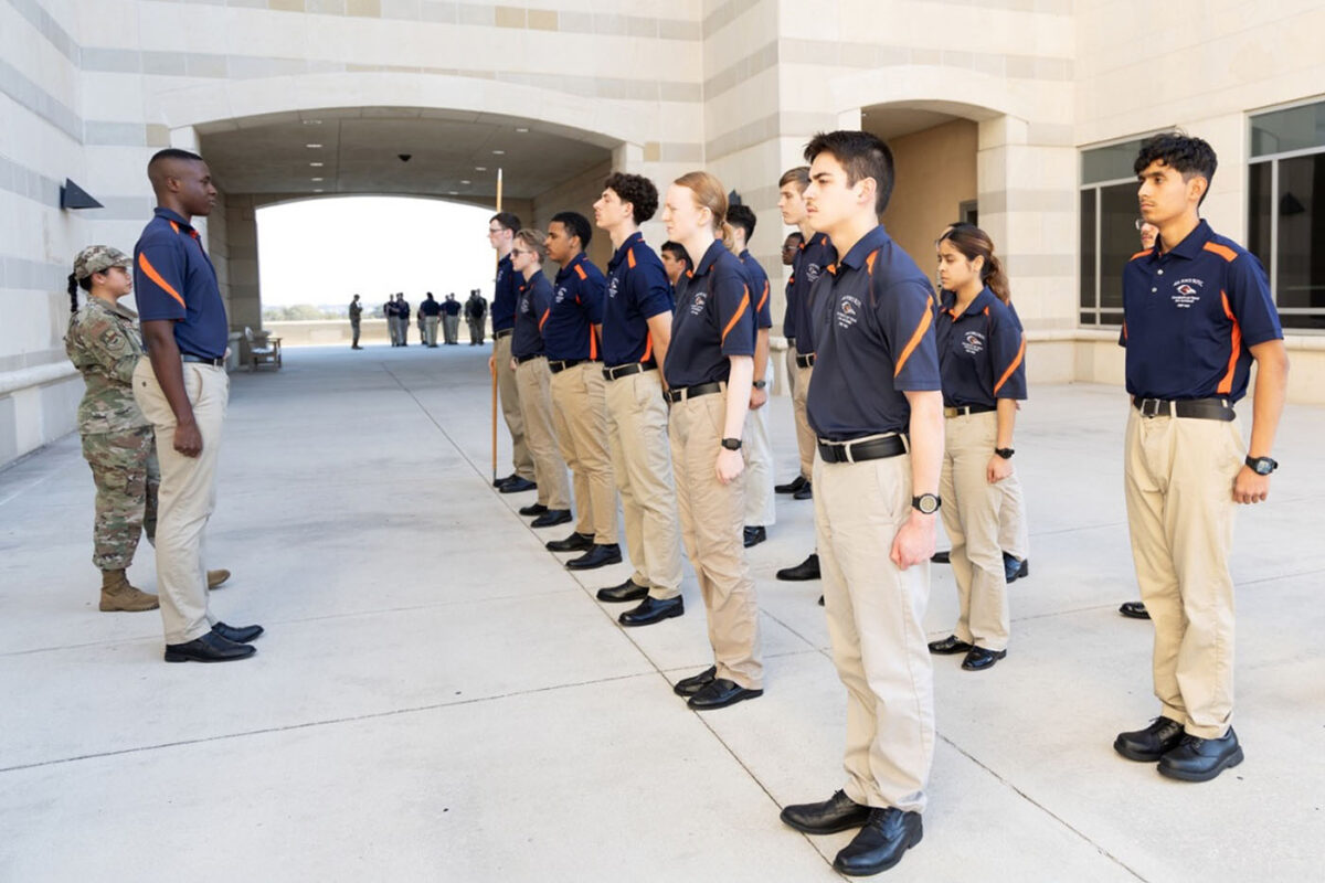 Cadets in blue polos stand at attention in the north breezeway of the Recreation Wellness Center.