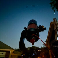 A telescope points up at a night sky.